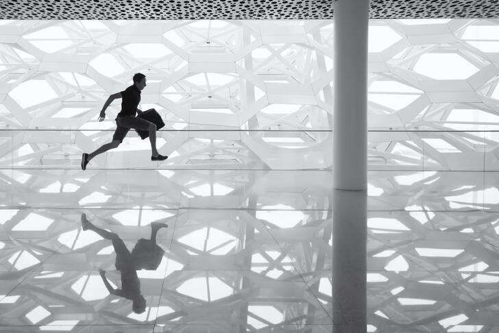 A man running through an empty airplane terminal.