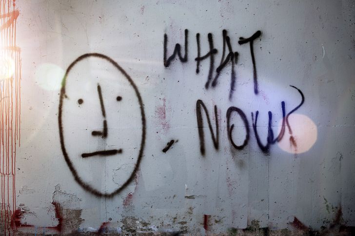 Grafitti on a wall saying 'what now?'